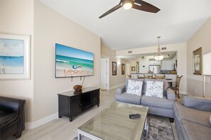 Una sala de estar con un sofá, una mesa de centro y un cuadro de una playa.