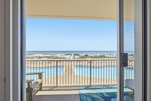 Un balcón con vista a la playa y una piscina.
