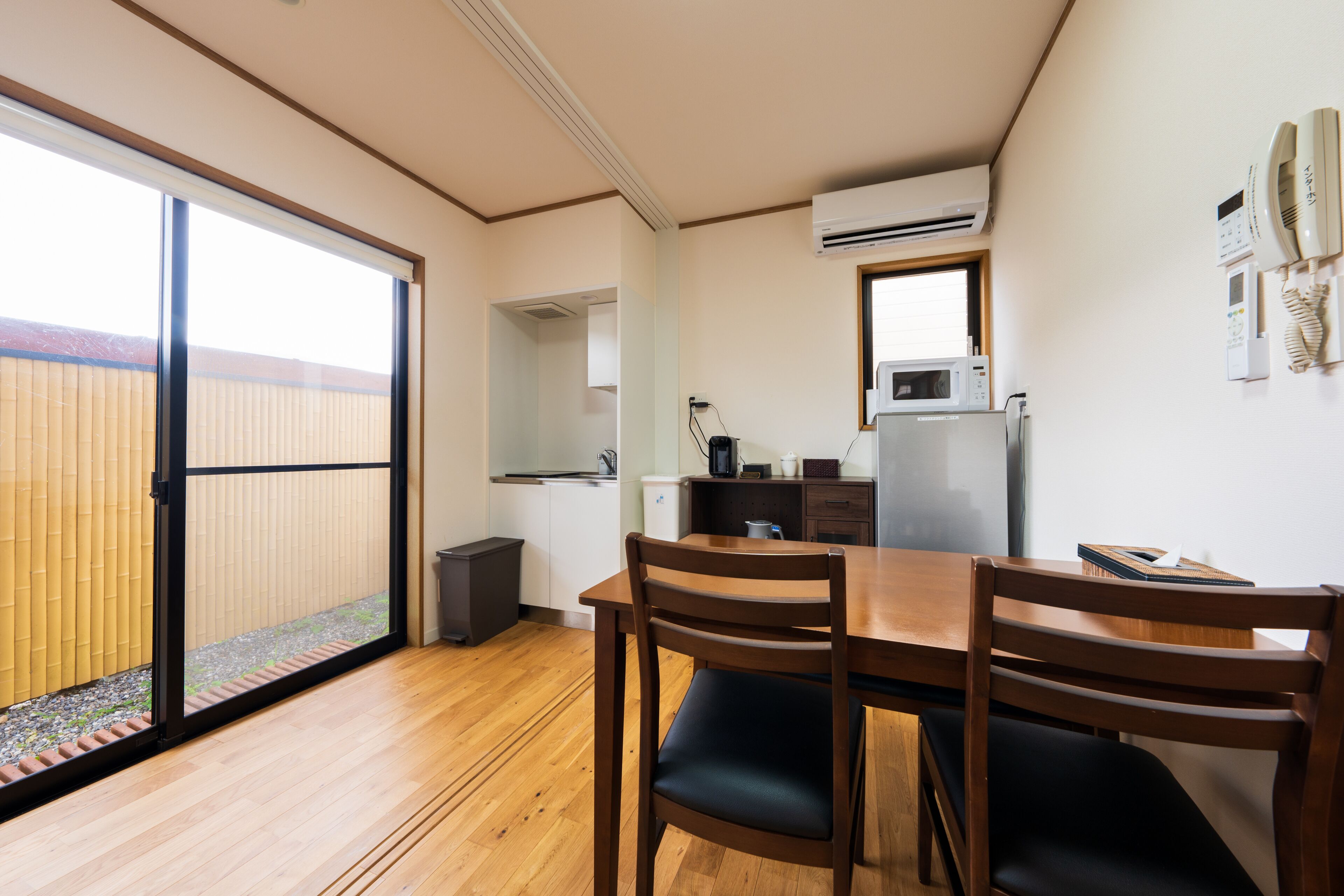 Cocina moderna equipada con microondas, estufa y lavaplatos. Se observa una mesa de comedor con sillas y una puerta corrediza de vidrio que da a un balcón.