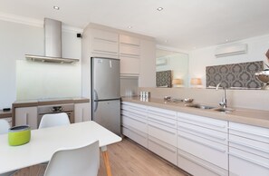 A modern kitchen with a stainless steel refrigerator, a built-in oven, and a gas stove. - Sandringham 45 (Cape Town)