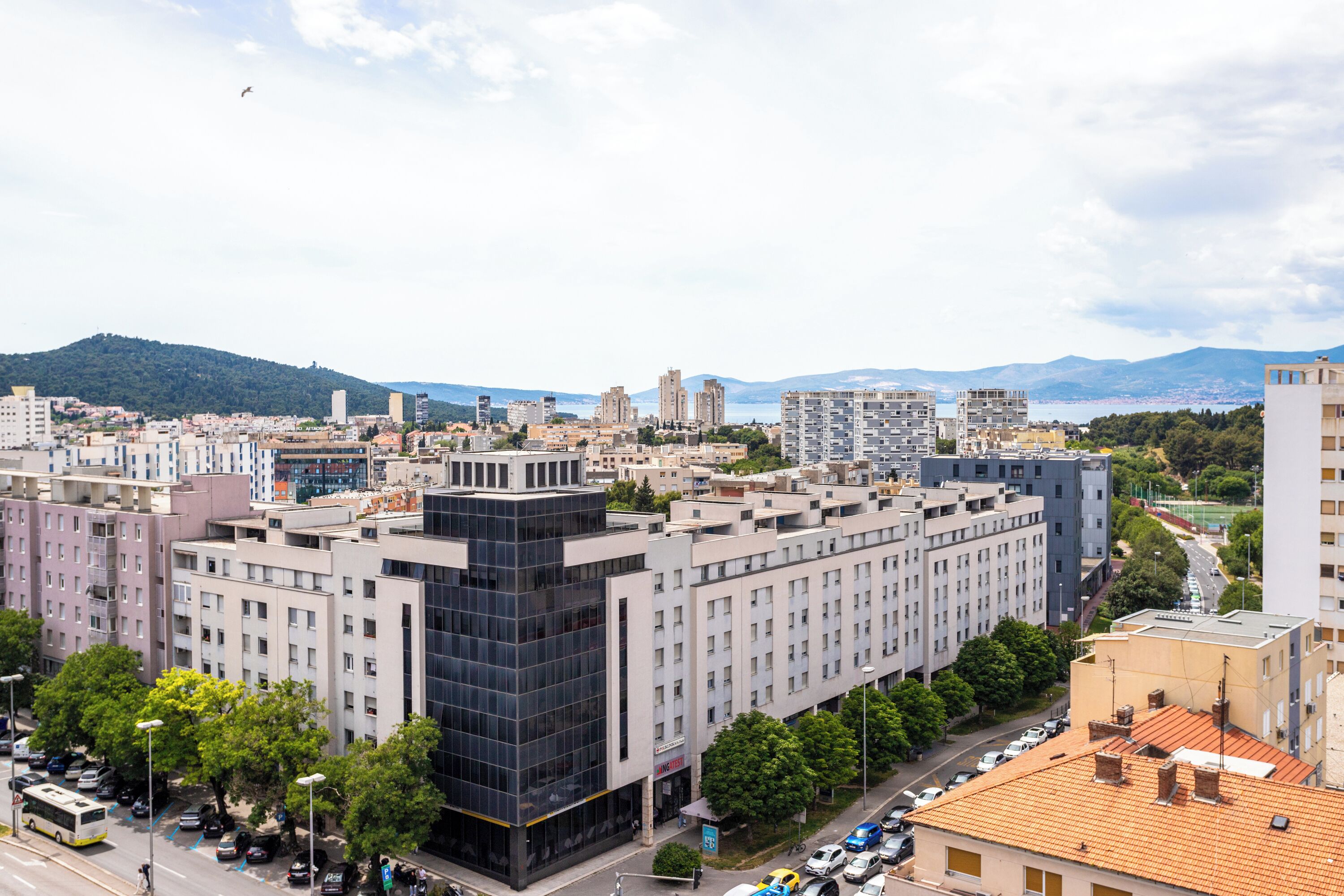 Un paisaje urbano con edificios modernos, cielo despejado y una vista distante de montañas.