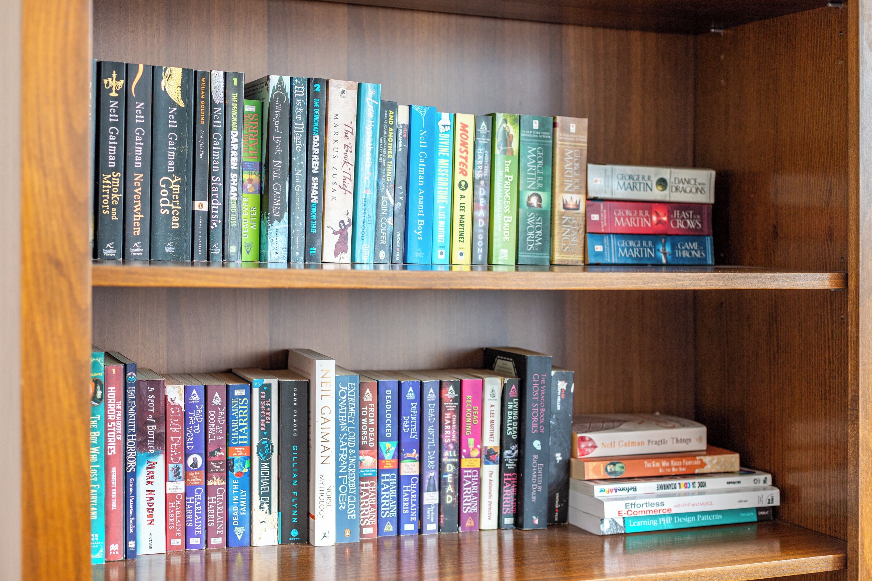 Una estantería con una variedad de libros, incluyendo algunos de Neil Gaiman y George R. R. Martin.