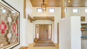 A hallway with a wooden bench, a rug, a large rug on the wall, and a door at the end. - Red Rock Views: Uptown Sedona Home Near Trails! (Sedona)