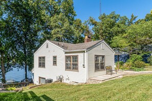 A white house with a dock, surrounded by trees and a lake. - Monticello Vacation Rental w/ Private Boat Dock! (Monticello)