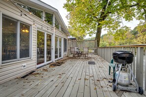 Una terraza de madera con una parrilla, mobiliario exterior y un porche cubierto.