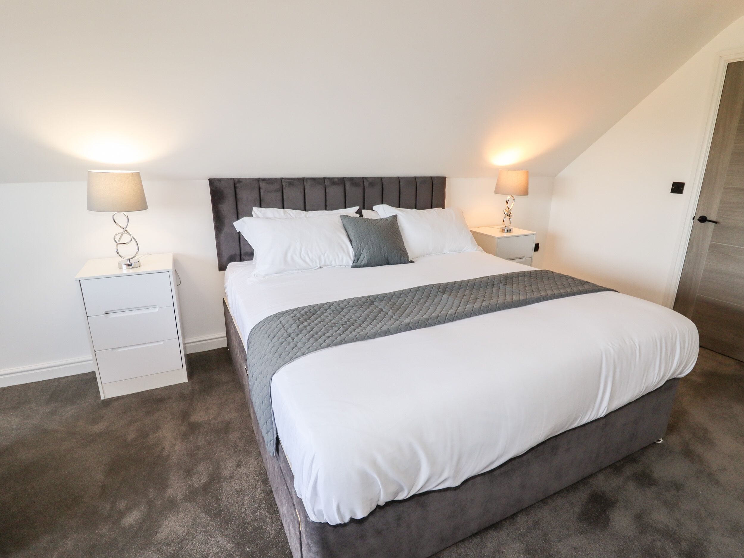A bedroom with a large bed, two bedside tables, and a headboard.