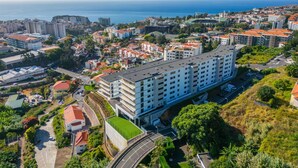 A multi-story hotel with a rooftop terrace, surrounded by a coastal cityscape. - Inner City by Homie in Funchal (Funchal)