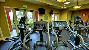 Un gimnasio con cintas de correr, elípticas y equipo de ejercicio.