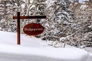 A wooden sign with the name "Ridgepoint" in a snowy landscape. - KBM Resorts | Ridgepoint | Ski-in/Ski-out access, Common Hot Tub, Summer pool, Tennis, Parking, in Silver Lake Deer Valley! RGT-117 (Park City)