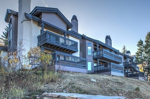 A multi-story building with balconies, a garage, and a stone retaining wall.