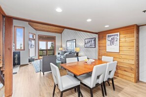 Ein modernes Interieur mit einem Holzesstisch, weißen Stühlen, einer Couch und einem Kamin.