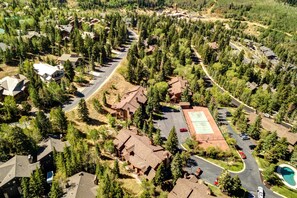 An aerial view of a residential area with multiple houses, a tennis court, and a swimming pool.