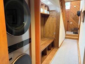 A compact RV interior with a built-in washer, wooden storage cabinets, and a bench.