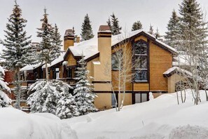 A lodge with a large wooden facade, multiple chimneys, and snow-covered surroundings. - KBM Resorts | Ridgepoint | Ski-in/Ski-out access, Common Hot Tub, Summer pool, Tennis, Parking, in Silver Lake Deer Valley! RGT-117 (Park City)