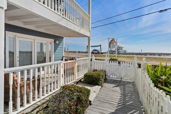 A two-story building with a balcony, a covered porch, and a view of the beach and ocean. - Summer Breeze 1-Bed Condo! Gorgeous Views & Pool | Steps to Beach | Book Now! (Miramar Beach)