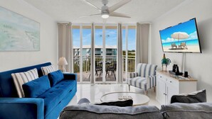 Un soggiorno con un divano blu, un tavolino da caffè e una TV che mostra una spiaggia.
