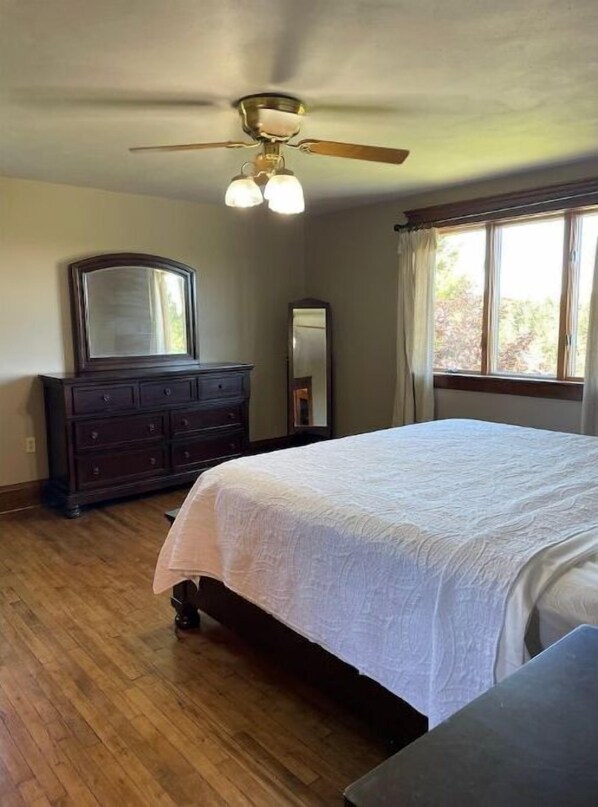 Une chambre à coucher avec un lit, une commode et un ventilateur de plafond.