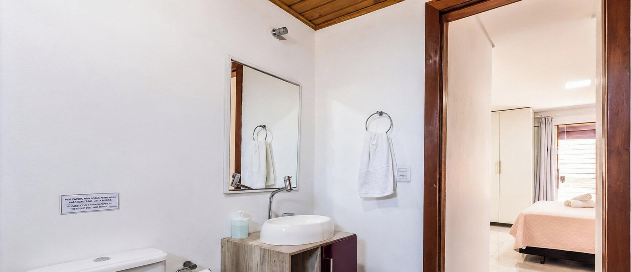 Une salle de bain équipée d’un WC, d’un lavabo, d’un miroir et d’un porte-serviettes.