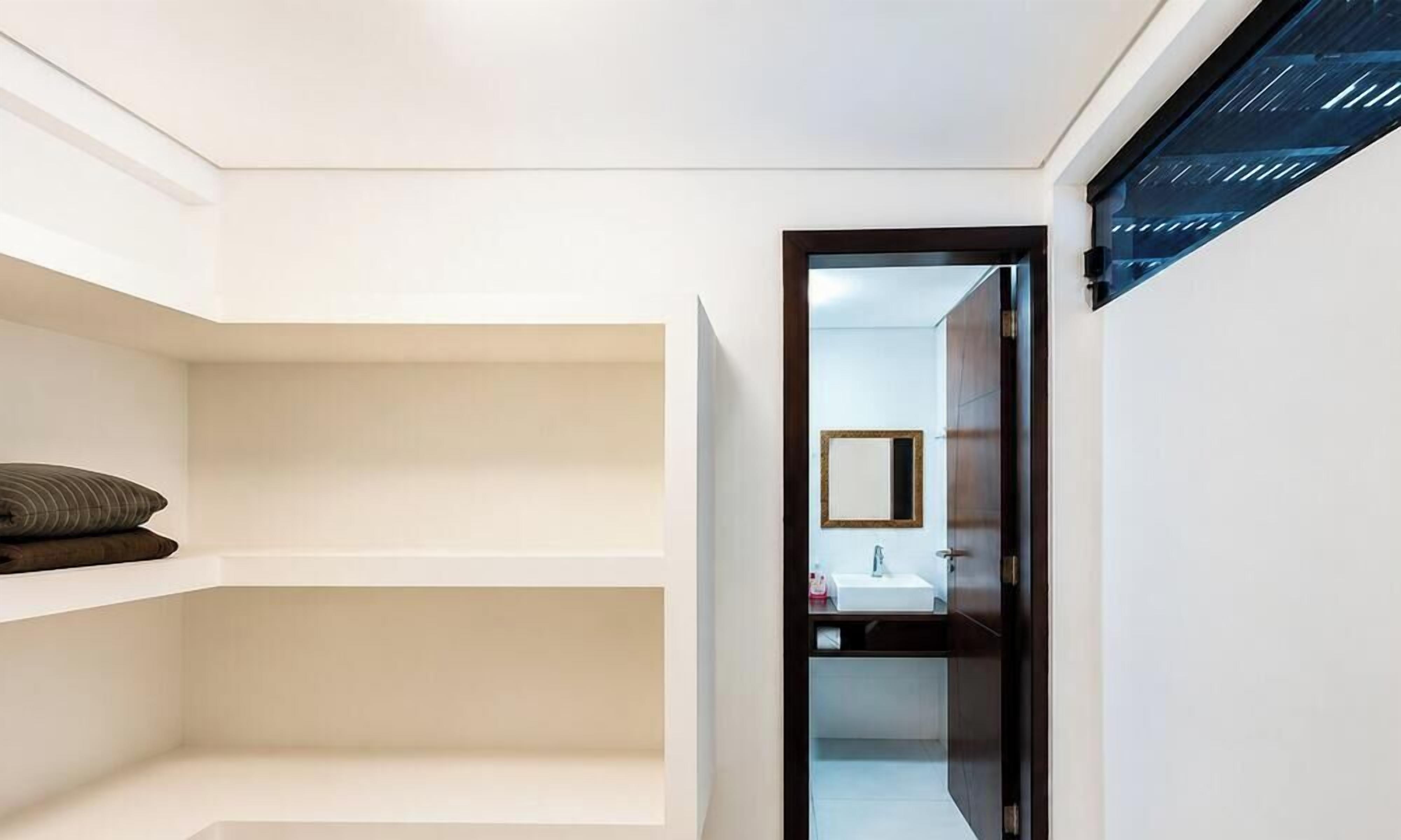 A modern bathroom with a white vanity, a mirror, and a dark door.