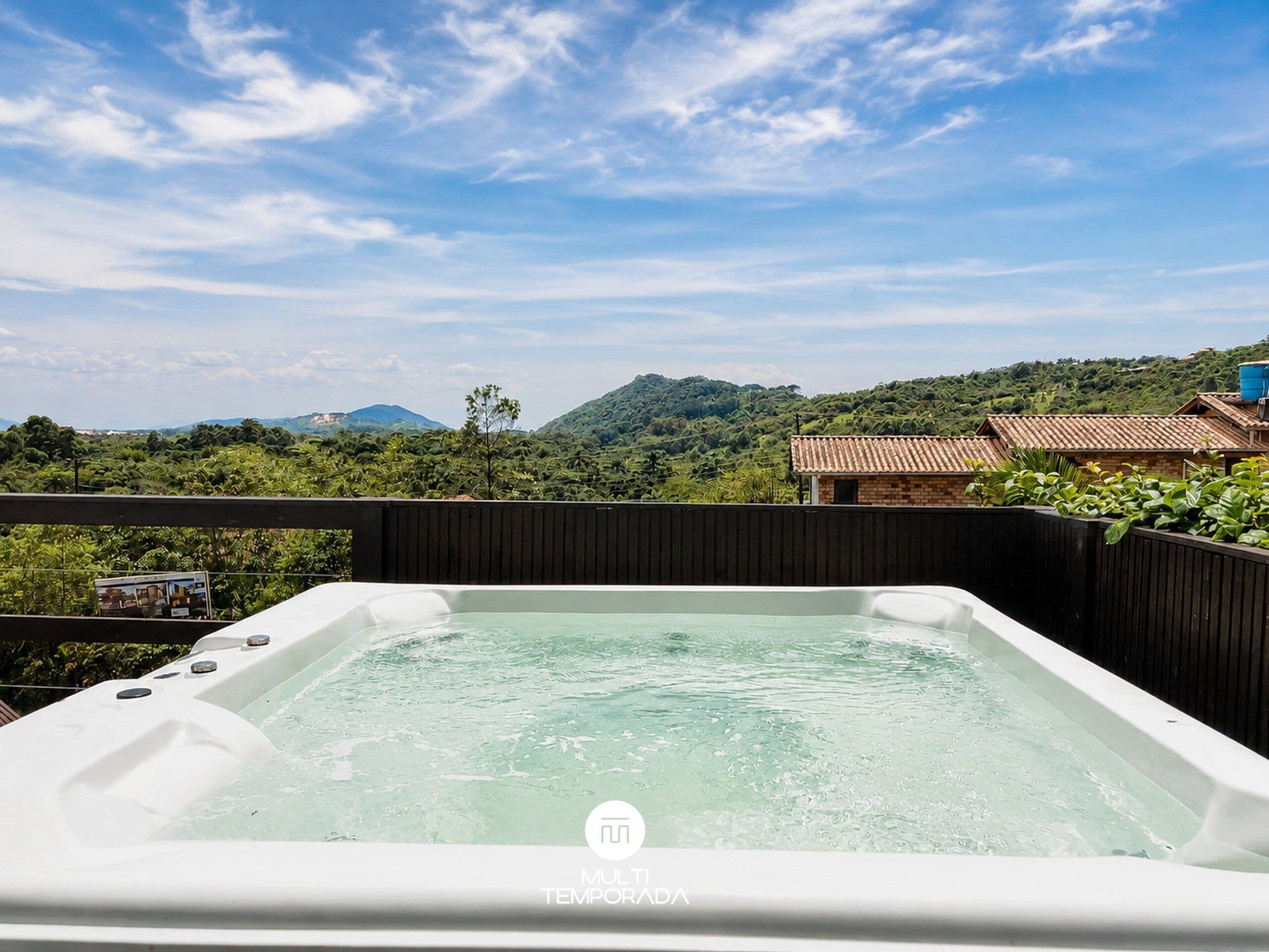 Un bain à remous avec vue sur un paysage montagneux et un petit bâtiment doté d’un toit en tuiles.