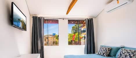 A bedroom with a bed, a TV, and a window with curtains.