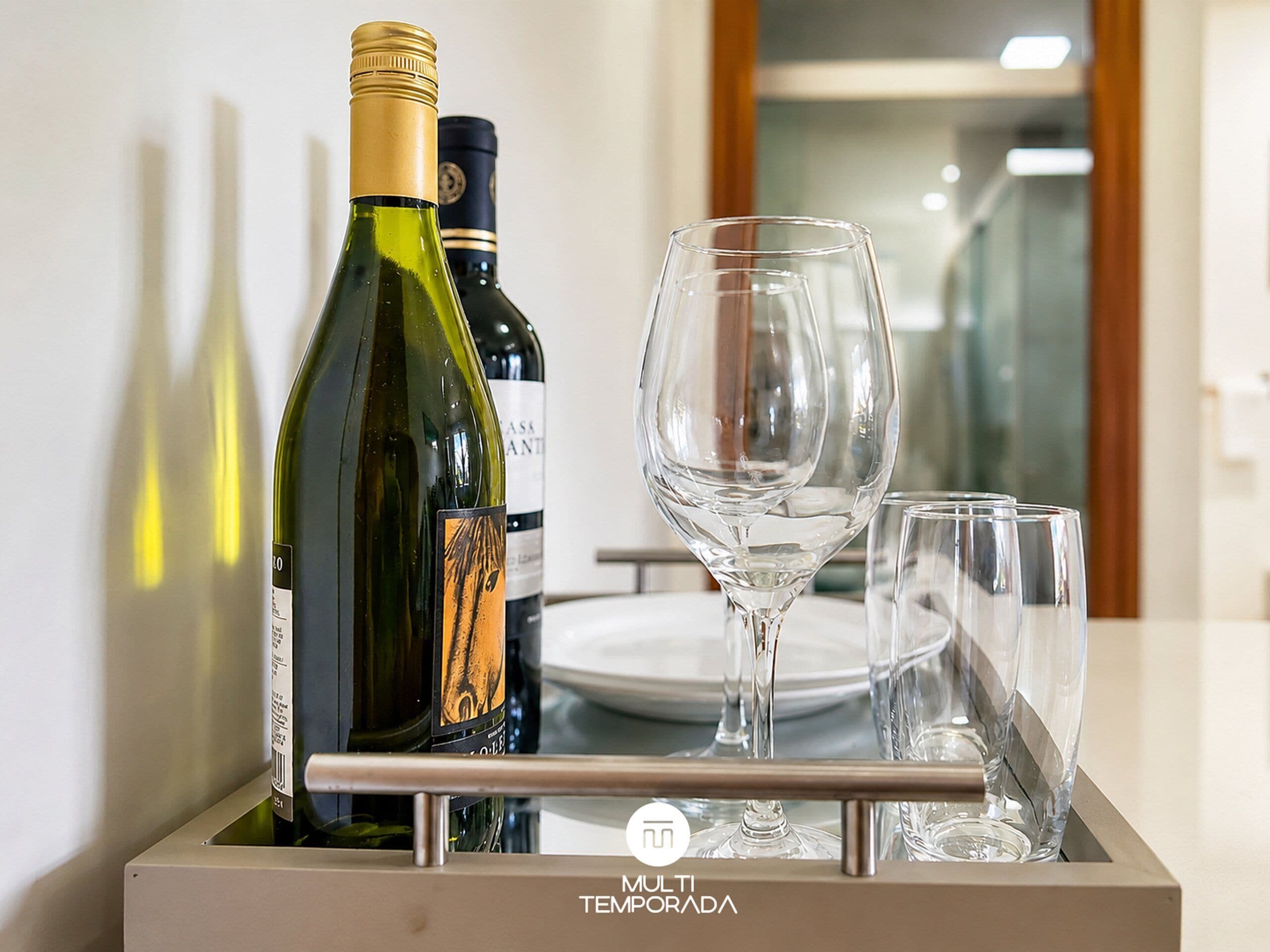Una nevera minibar con botellas de vino y copas.