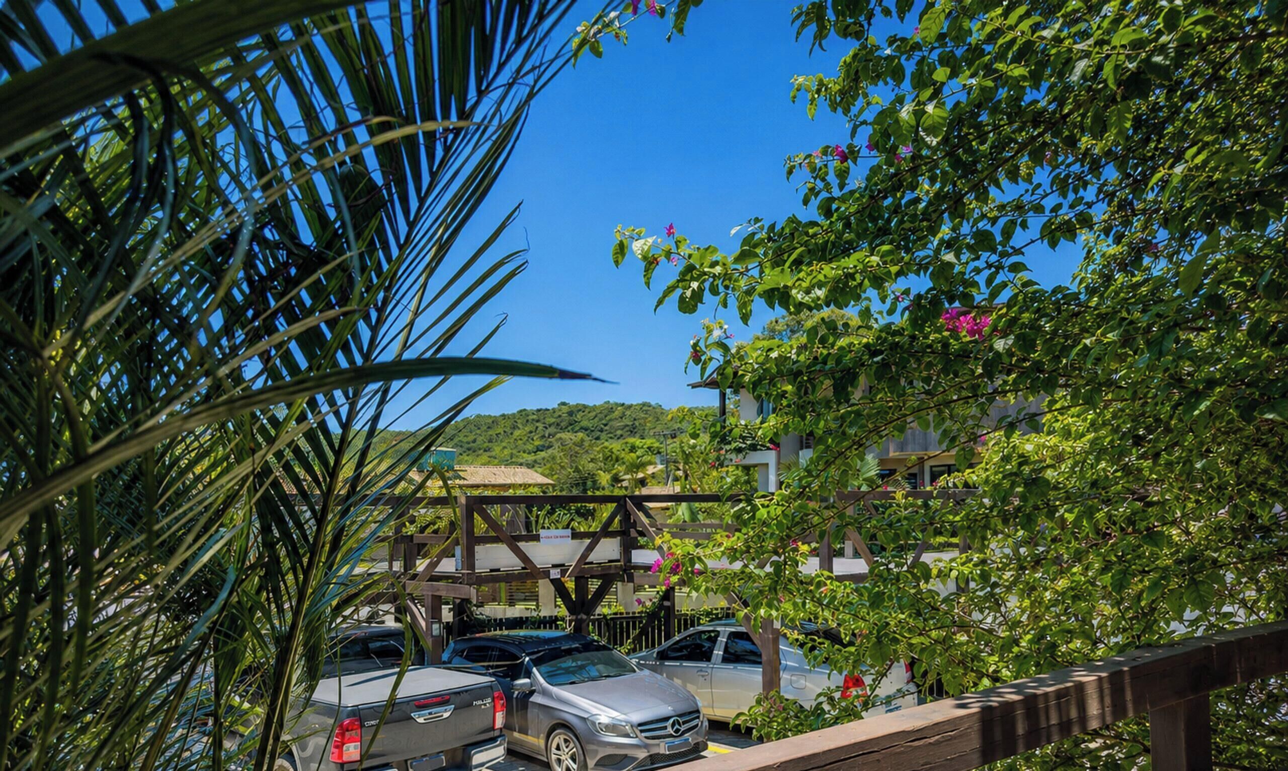 A parking area with cars, a wooden structure, and lush greenery.