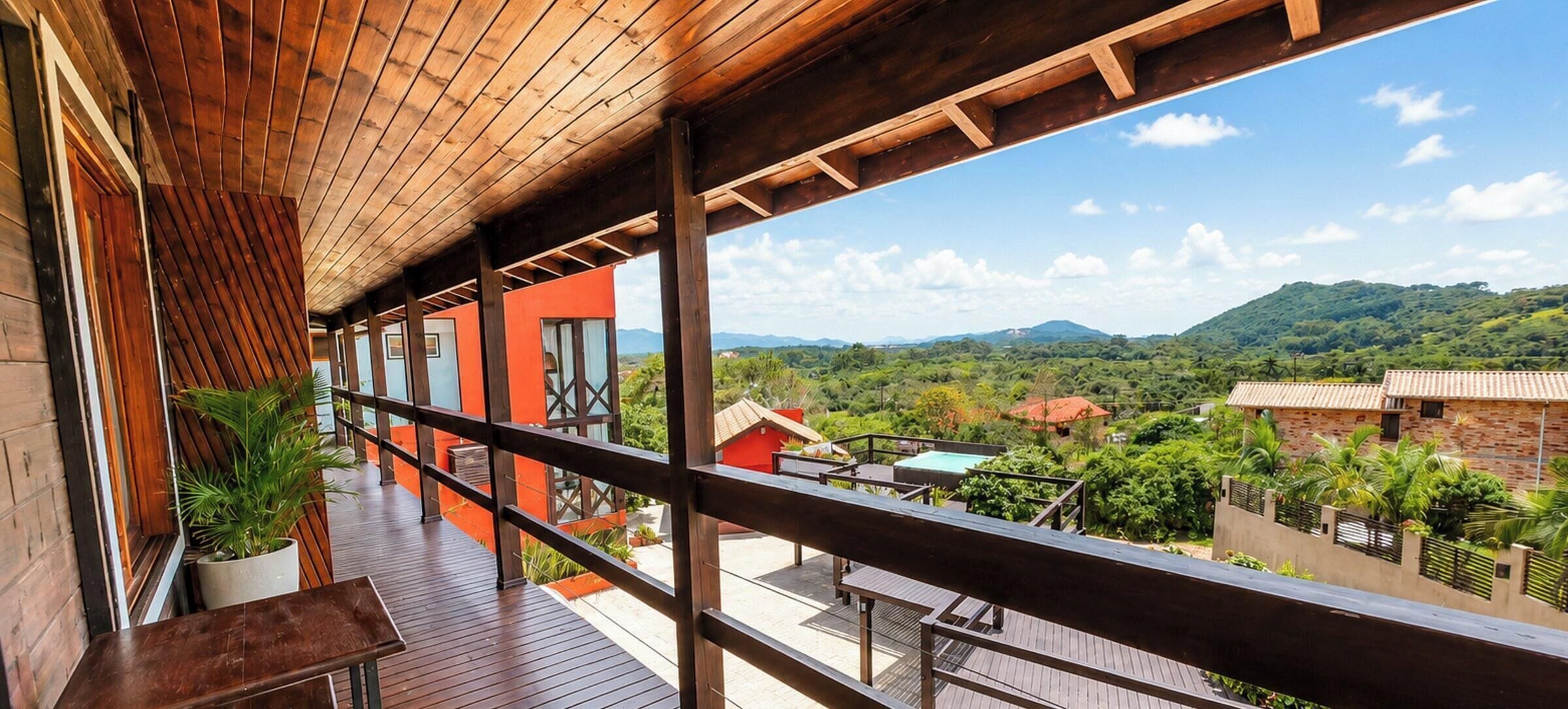 Un balcón de madera con vistas a un paisaje exuberante y montañas distantes.