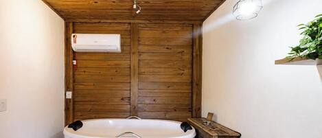 Un baño con techo de madera, una bañera blanca y un aire acondicionado de pared.