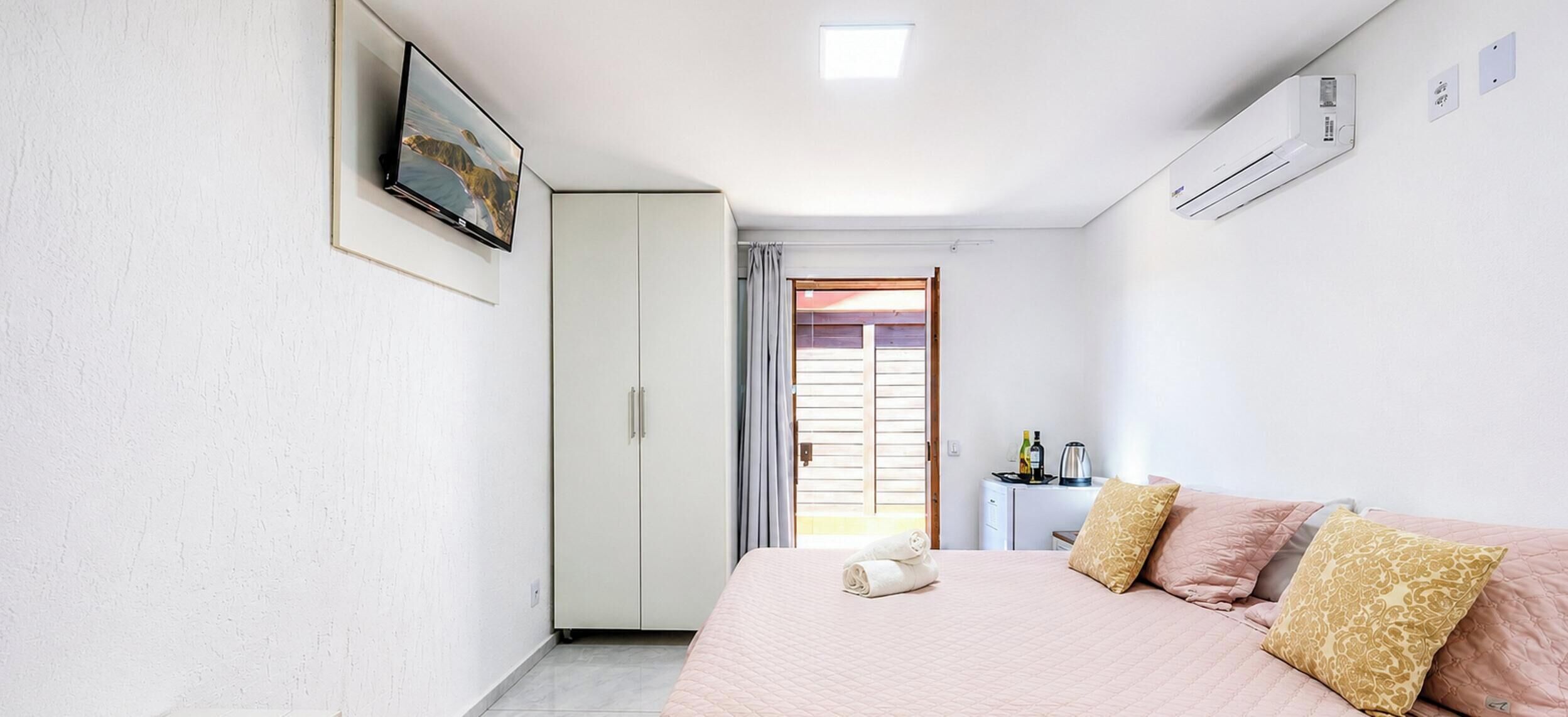 Une chambre à coucher comprenant un lit, une armoire, un téléviseur et un appareil de climatisation.