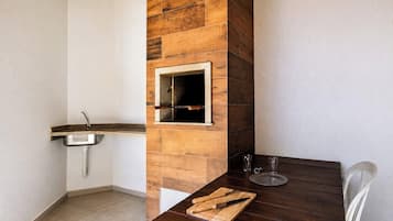 Uma cozinha com painel de parede de madeira, pia e mesa com tábua de corte e utensílios.