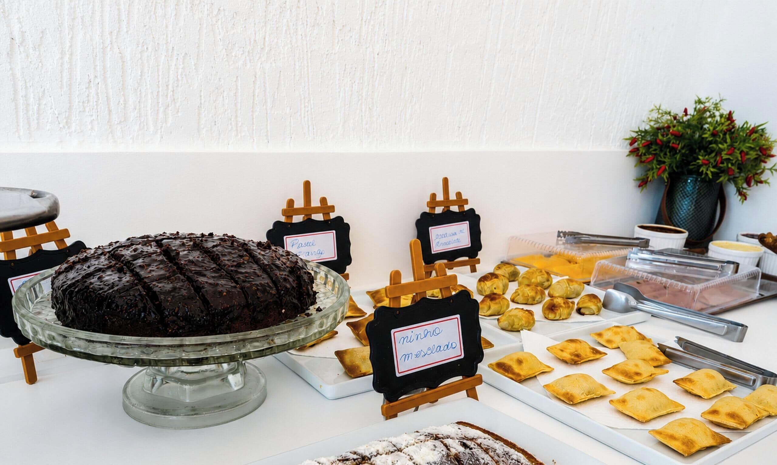 A buffet table with various food items, including a chocolate cake, pastries, and labeled dishes.
