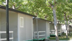 A row of single-story cabins with a simple, functional design, each featuring a small porch and a window. - New Village Europe  (Vasto)