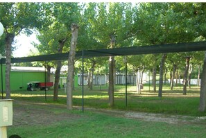 Relax in a serene outdoor space surrounded by trees and a shaded pergola, perfect for unwinding or enjoying the surroundings.