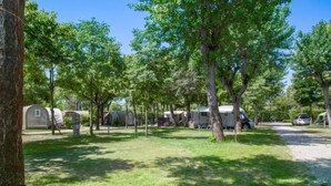 A campsite with RVs and mobile homes, surrounded by trees and grassy areas. - New Village Europe  (Vasto)