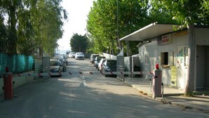 A street with parked cars and a building with a sign. - New Village Europe  (Vasto)
