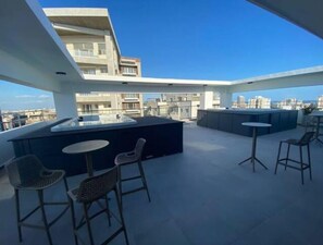 Enjoy panoramic views of the city from this rooftop terrace with a central seating area and bar.