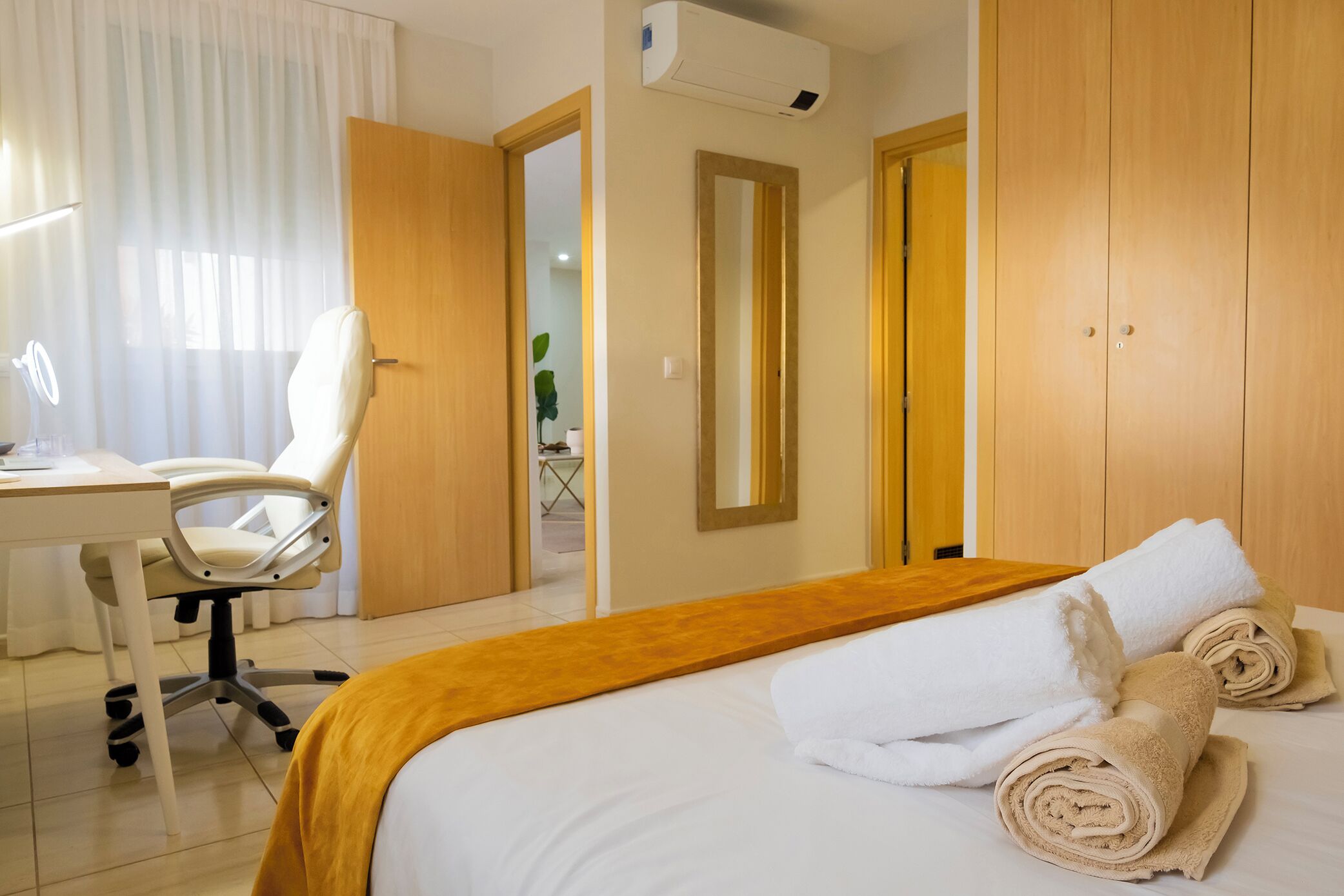 Ein Hotelzimmer mit einem Bett, einem Schreibtisch mit Stuhl, einem Spiegel und einem Kleiderschrank.