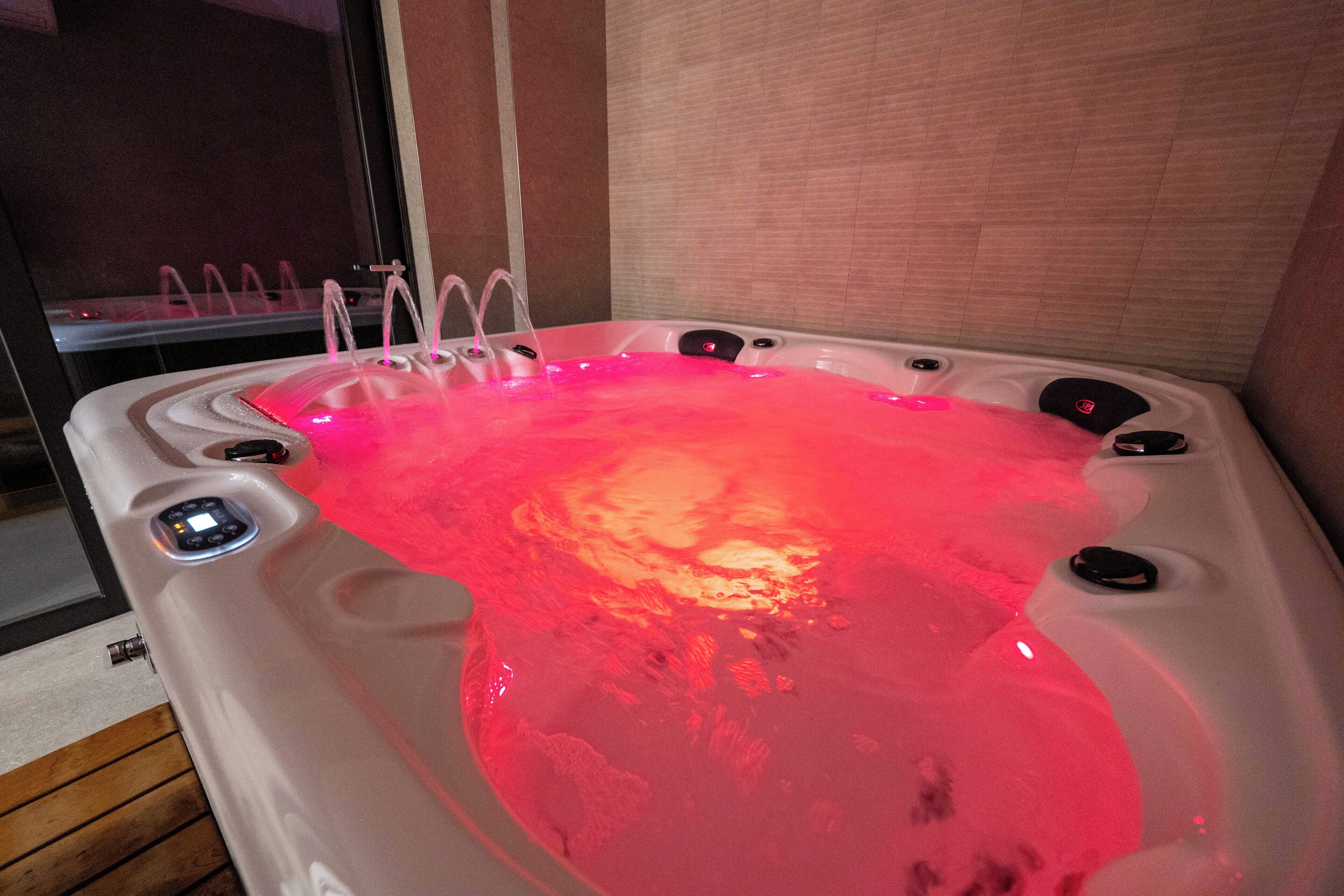 Una vasca idromassaggio con pannello di controllo digitale, una fontana integrata e vista all'esterno tramite una porta in vetro.