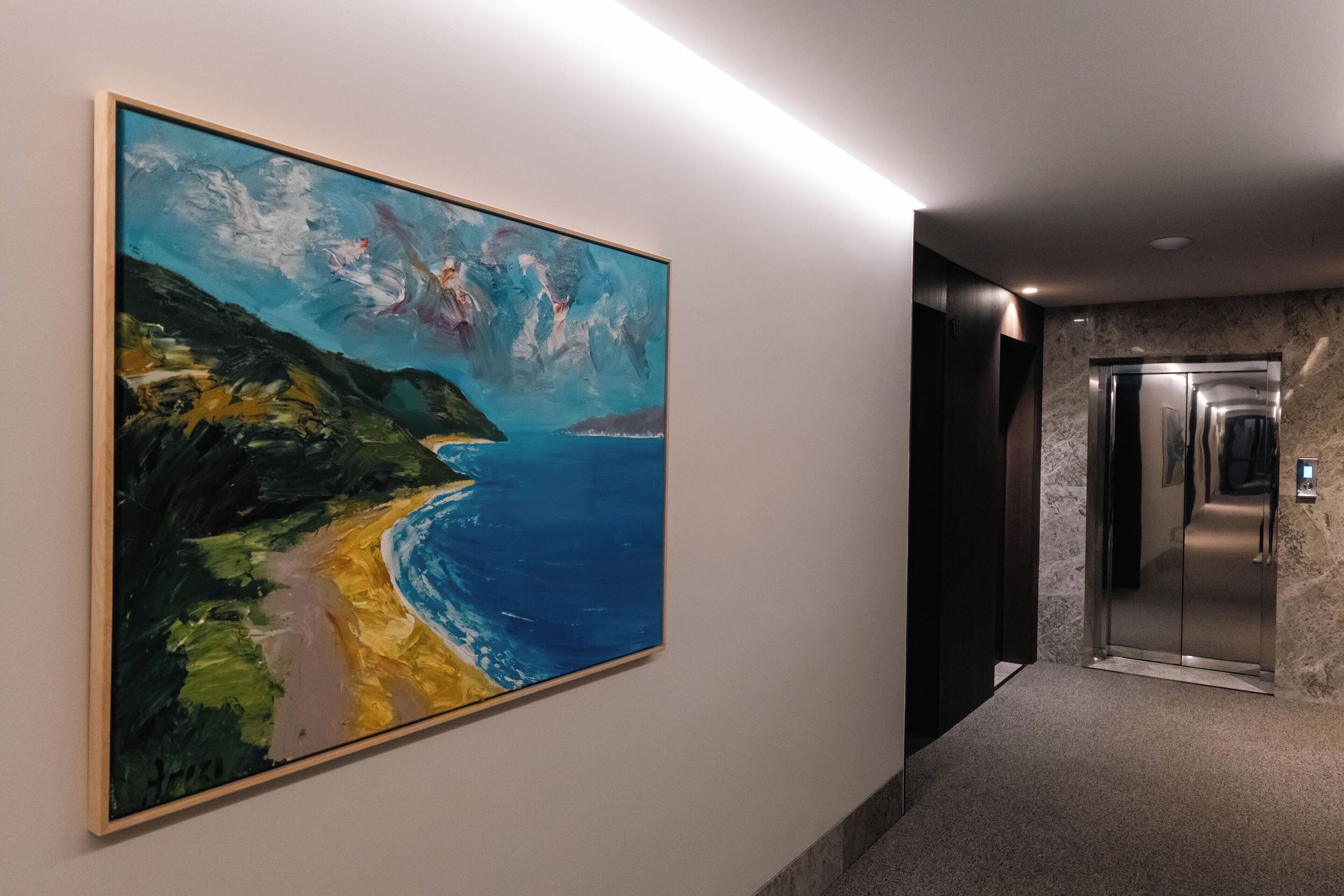 A hallway with a large abstract painting on the wall, a marble floor, and an elevator.