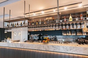 A bar area with shelves of bottles and glasses, a marble countertop, and a fruit display.