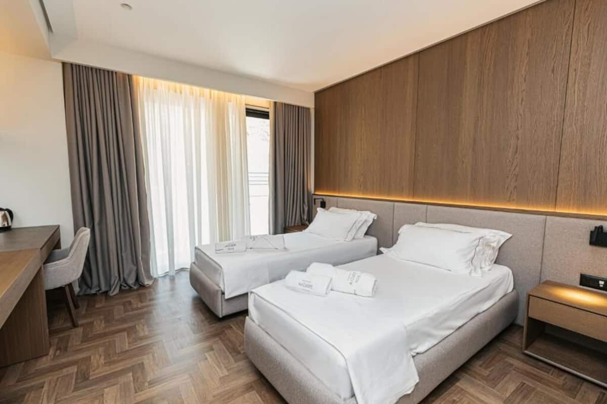 Een hotelkamer met twee bedden, een bureau en een stoel.