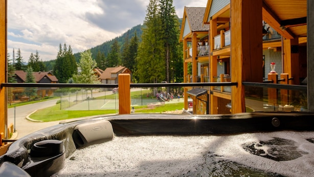 A hot tub area with a view of a wooden building and surrounding landscape.