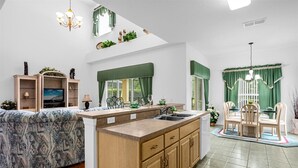 Une cuisine moderne dotée d’un îlot central, d’un coin repas avec une table ronde et d’étagères intégrées où sont exposés des objets décoratifs.