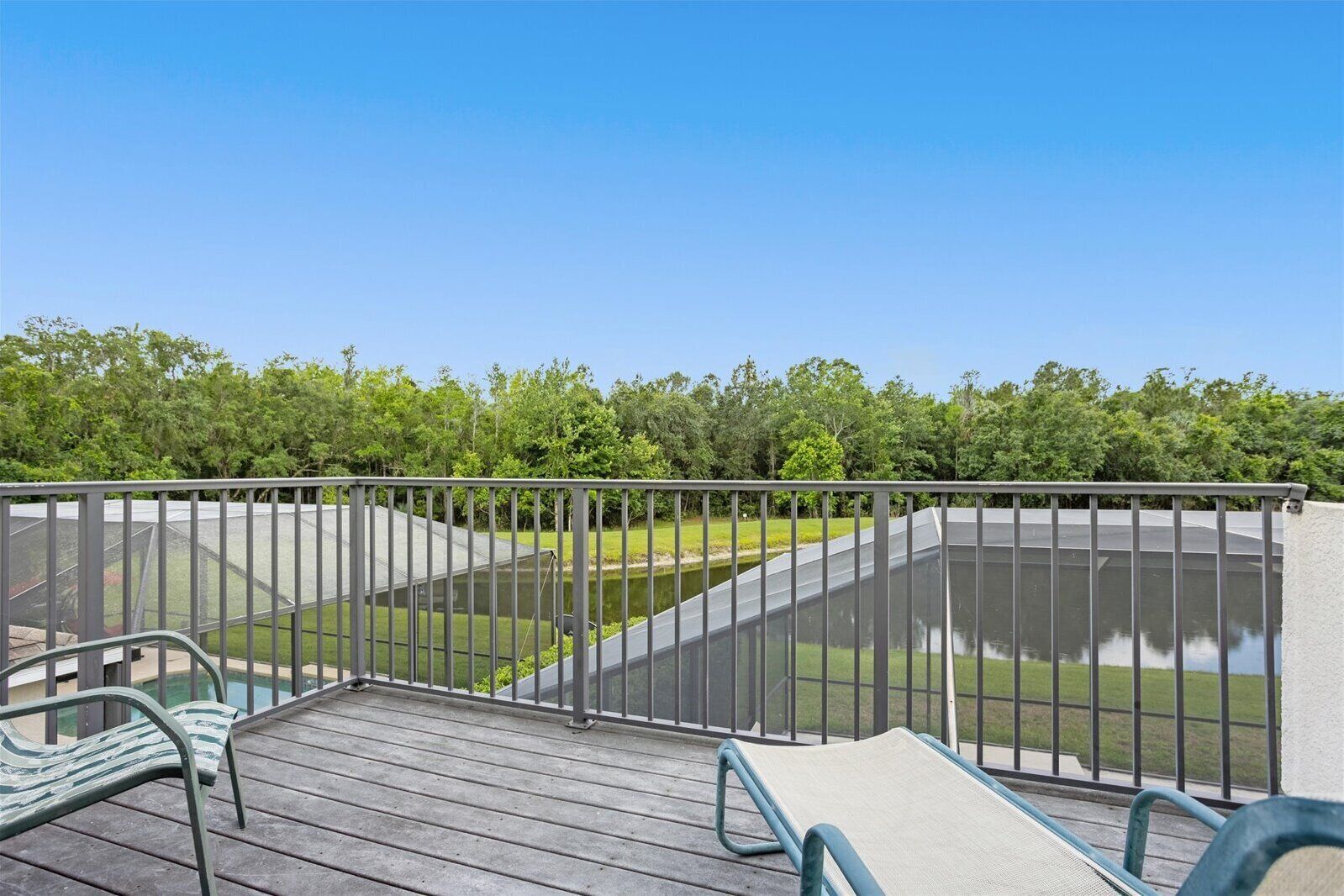 A balcony with a view of a water feature and a forested area.