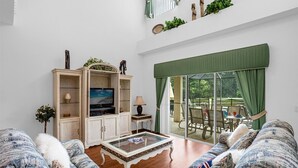 Un salon spacieux doté d’un grand téléviseur, de sièges confortables et offrant une vue sur l’extérieur.