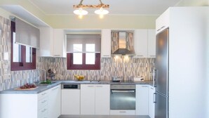 Una cocina moderna con armarios blancos, horno empotrado y refrigerador de acero inoxidable.