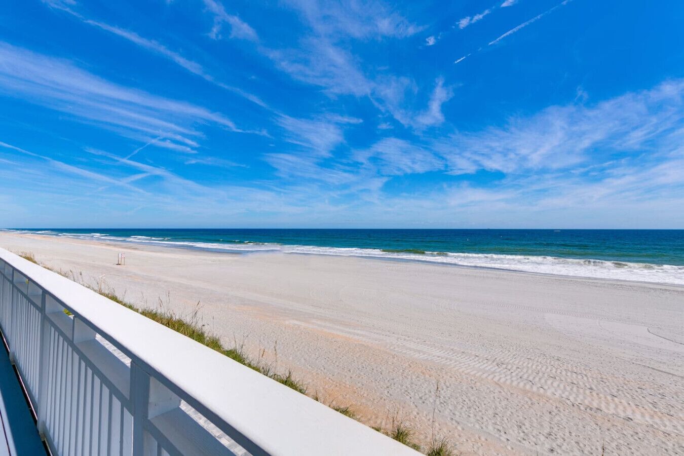 A beach with a white fence and ocean view.