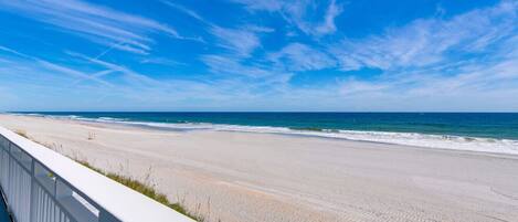 A beach with a white fence and ocean view.