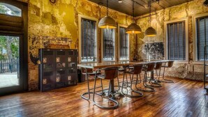 Un coin bar au style rustique, avec un plancher en bois, des tabourets de bar en métal et des lampes suspendues.